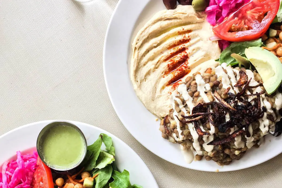 Overhead shot of two Mjadra plates with salad and hummus from Cafe Nuba - the best vegan restaurants in Vancouver.