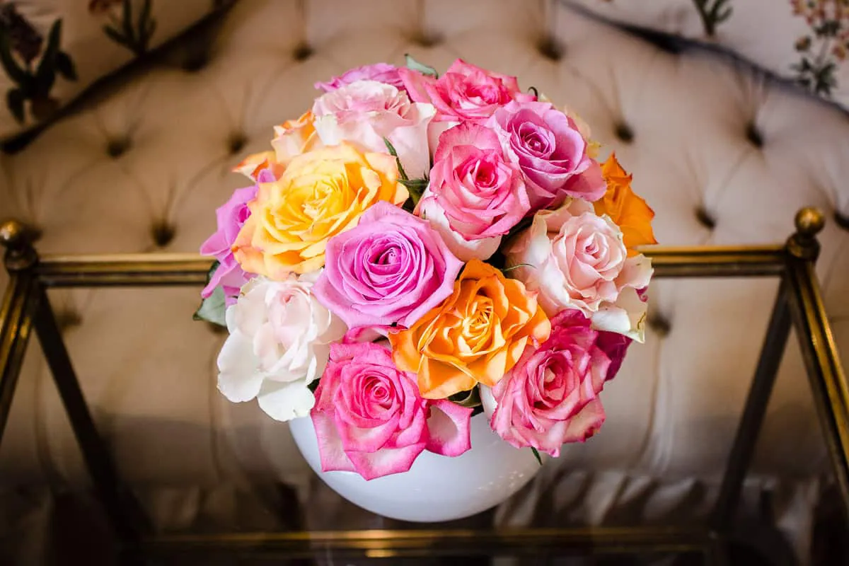 Image shows a vase of pink and yellow roses on a coffee table in the sitting room of Egerton House Hotel.