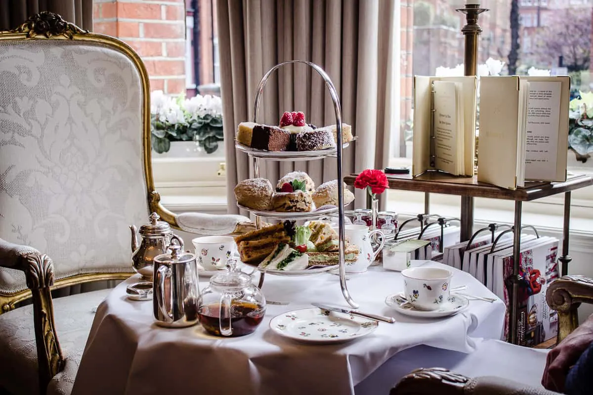 Image of My Favourite Vegan Restaurants in London - vegan afternoon tea stand on table surrounded by tea pots, cups, plates and menus at Egerton House Hotel