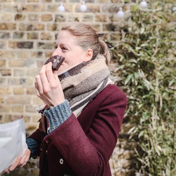 Image of My Favourite Vegan Restaurants in London - woman eating chocolate brownie outside by a brick wall at WAVE