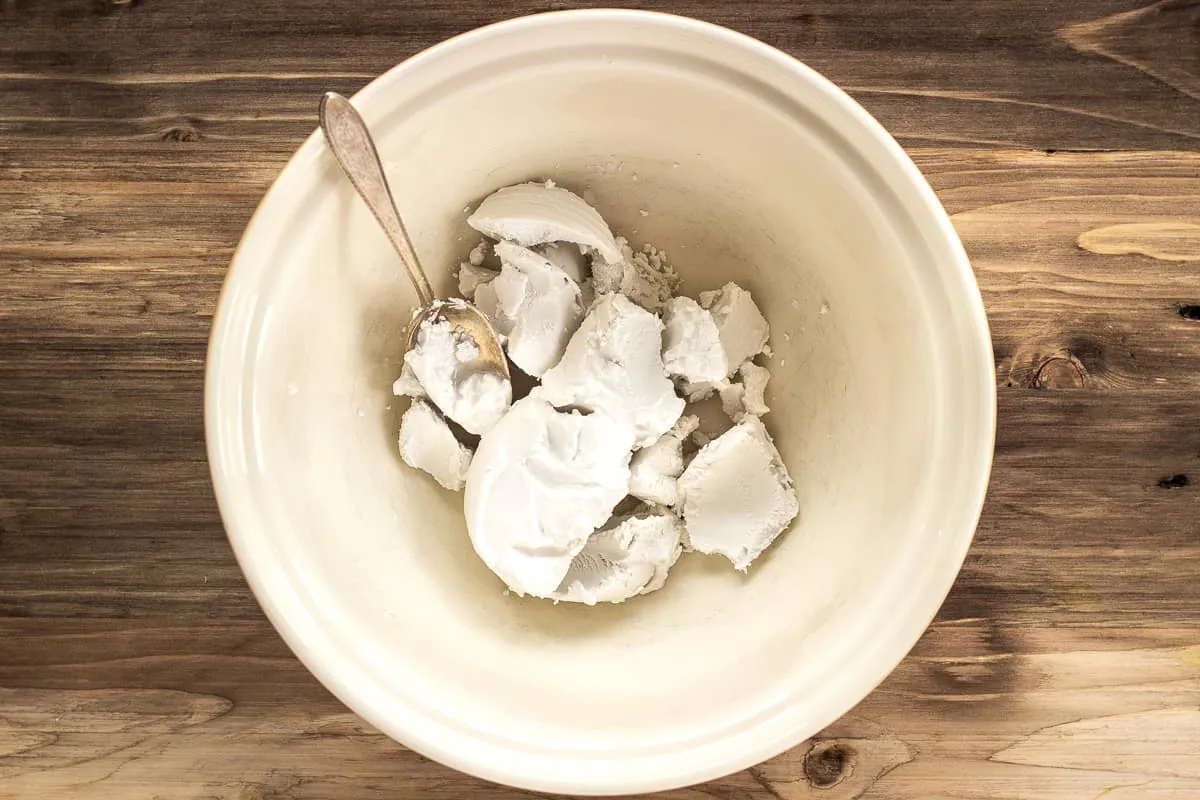 Image shows hardened coconut cream scraped into a large mixing bowl with a silver spoon.
