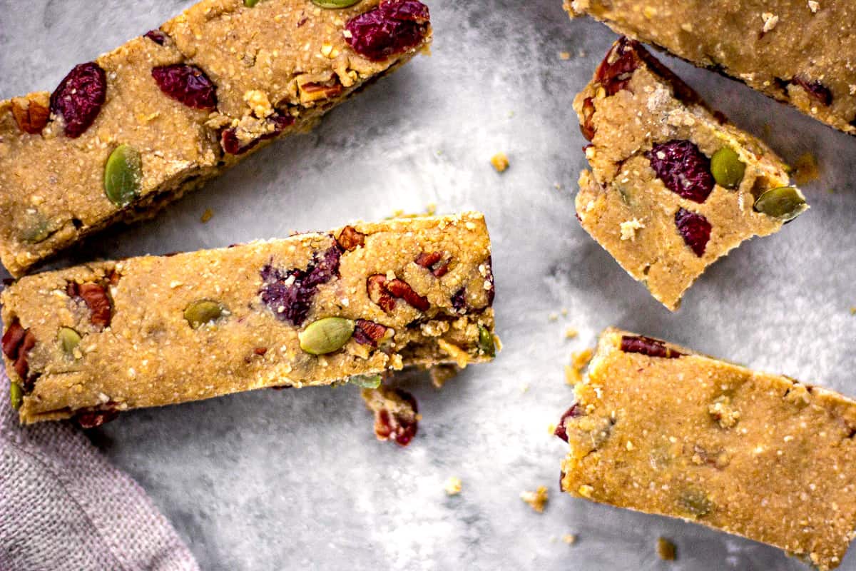 Image of vegan granola bars with cranberries, nuts and pumpkin seeds on a grey mottled background.
