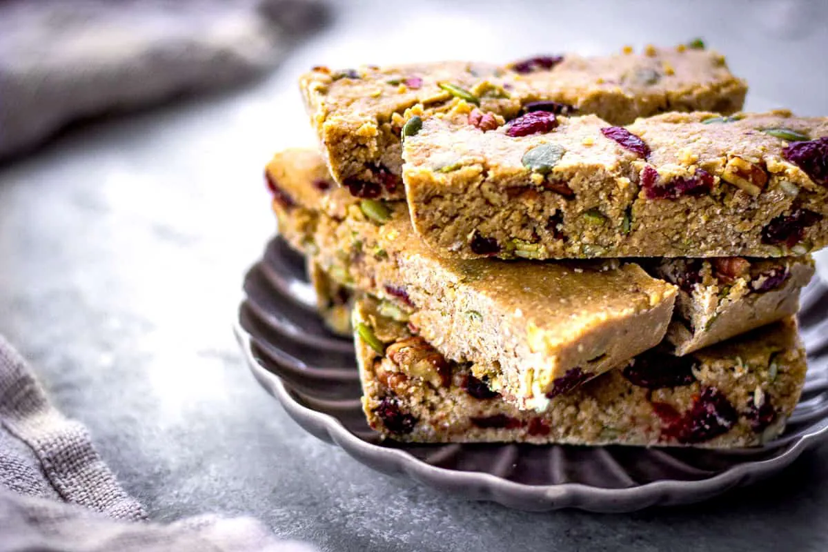 Image of vegan granola bars with cranberries, nuts and pumpkin seeds on a grey patterned plate.