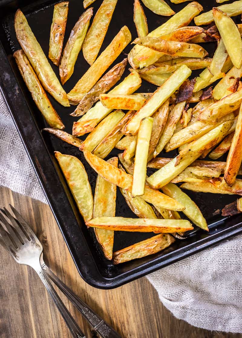 Oven cooked potato fries on a baking sheet.