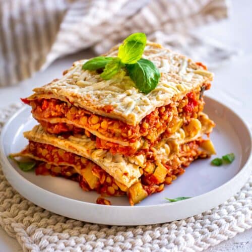 Image shows a large wedge of vegan lentil lasagna on a white plate.
