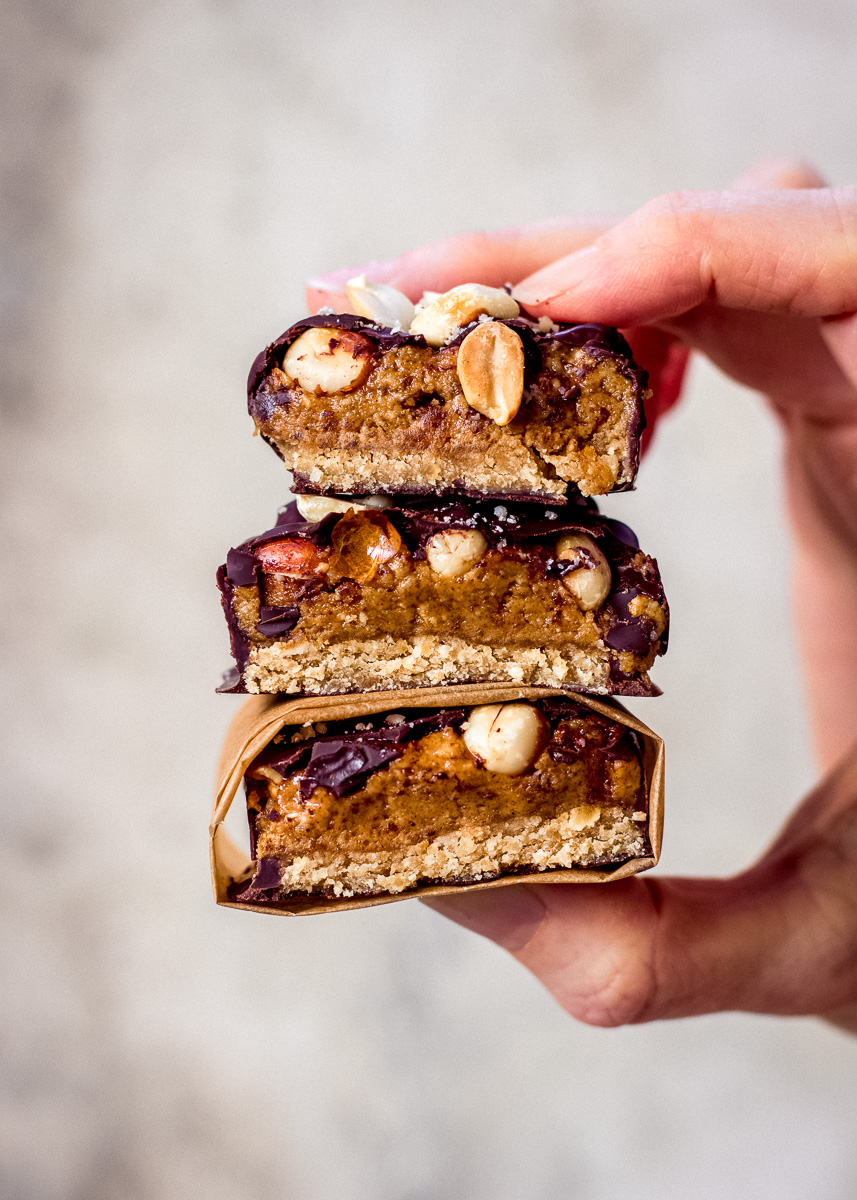 A woman holding No Bake Snickers Bars with cross-section of the inside of the bars visible.