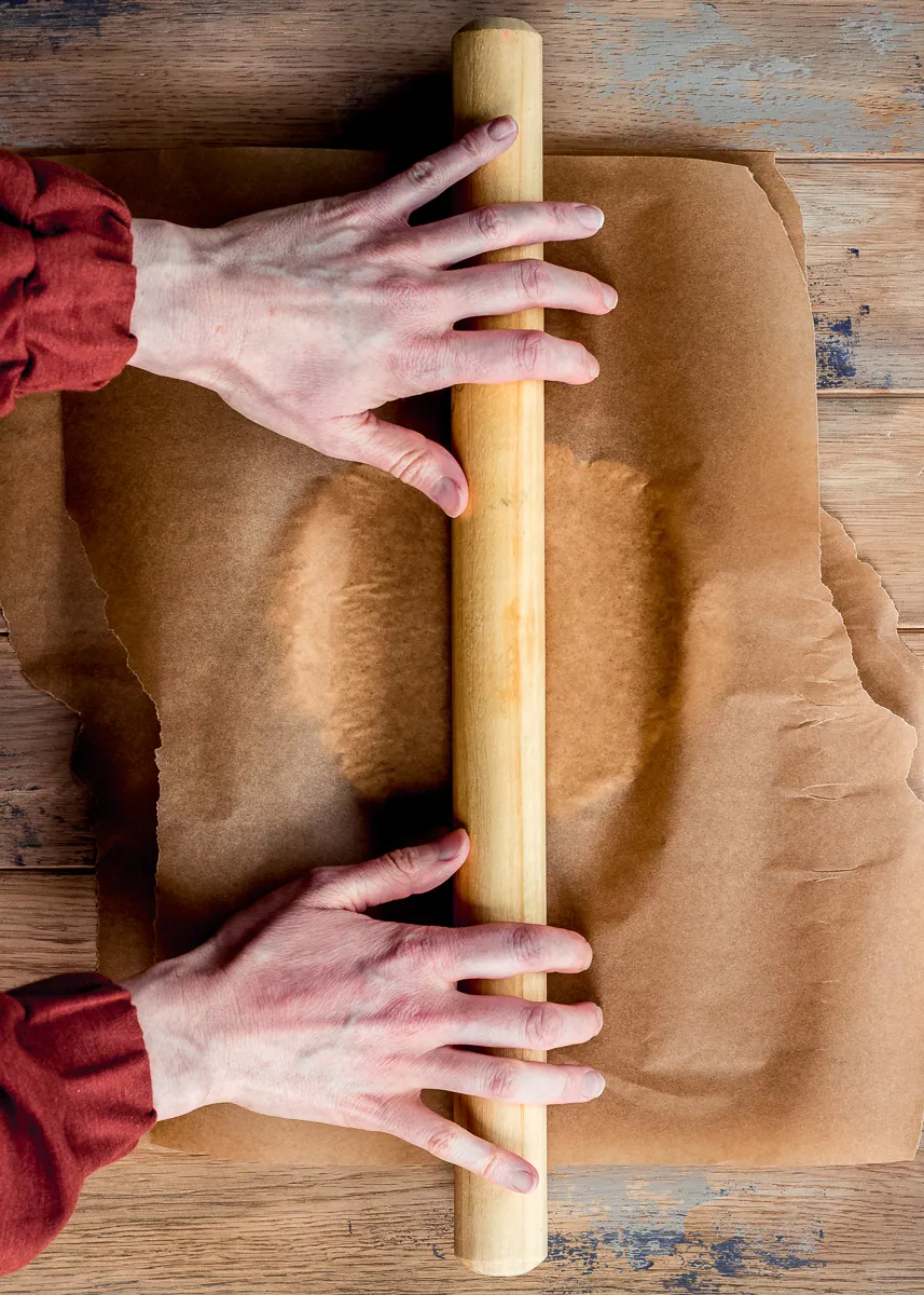 Pastry being rolled out with a rolling pin.