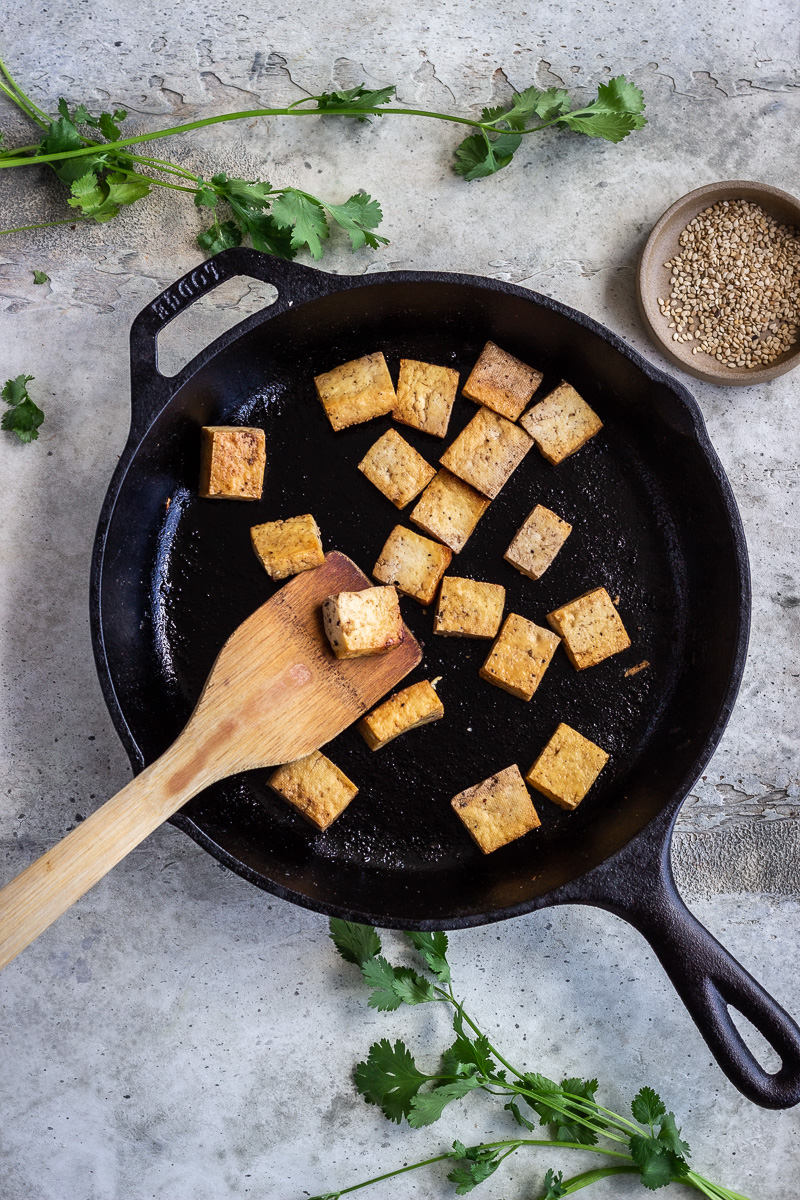 Tofu being cooked in a cast iron pan.