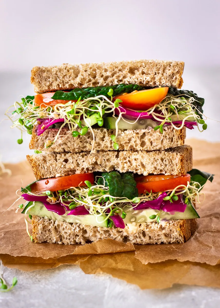 A colourful sandwich filled with alfalfa sprouts and mixed vegetables.