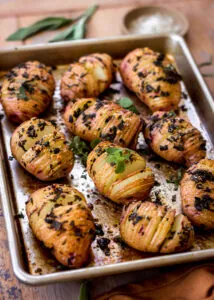 Sliced potatoes on a baking tray sprinkled with sage.