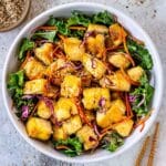 Healthy crispy tofu in a bowl garnished with salad and sesame seeds.
