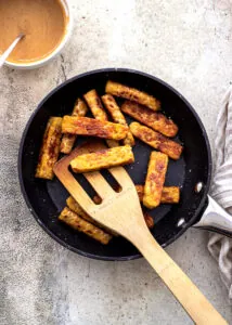Tempeh being fried in a small frying pan.
