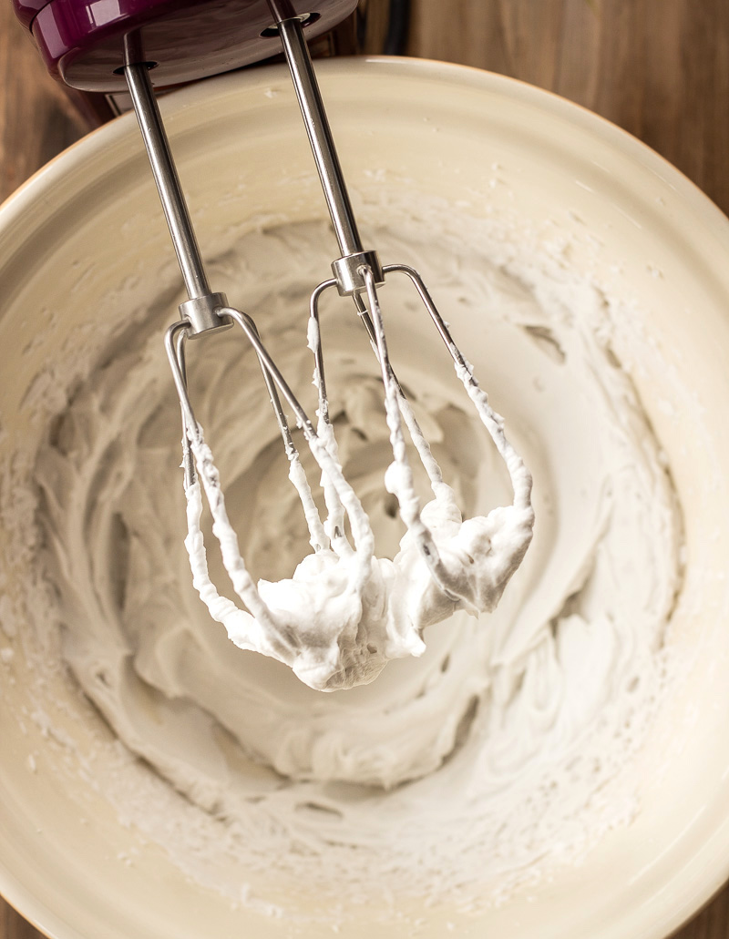 Beaters of electric whisk covered in coconut whipped cream.