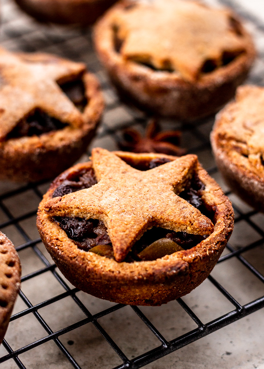 Mince tarts with pastry stars on top, on a black cooling rack.
