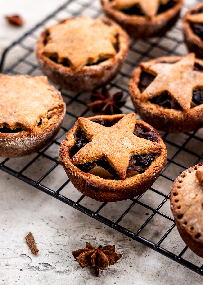 Mince tarts with pastry stars on top, on a black cooling rack.