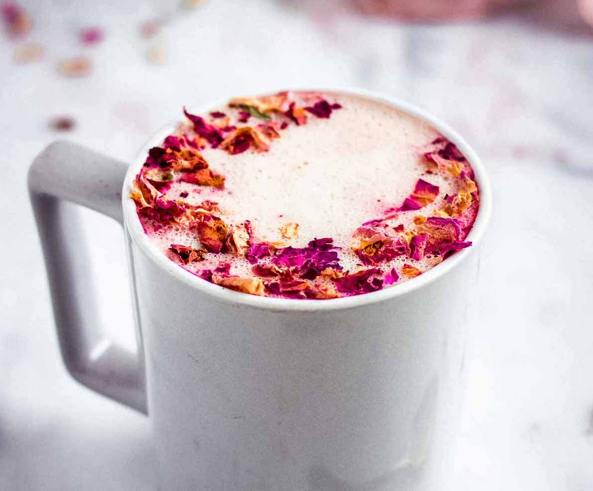 Rose latte in a mug decorated with rose petals.