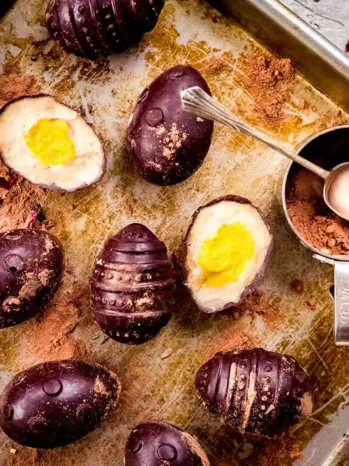 Vegan creme eggs on baking tray with cocoa powder.