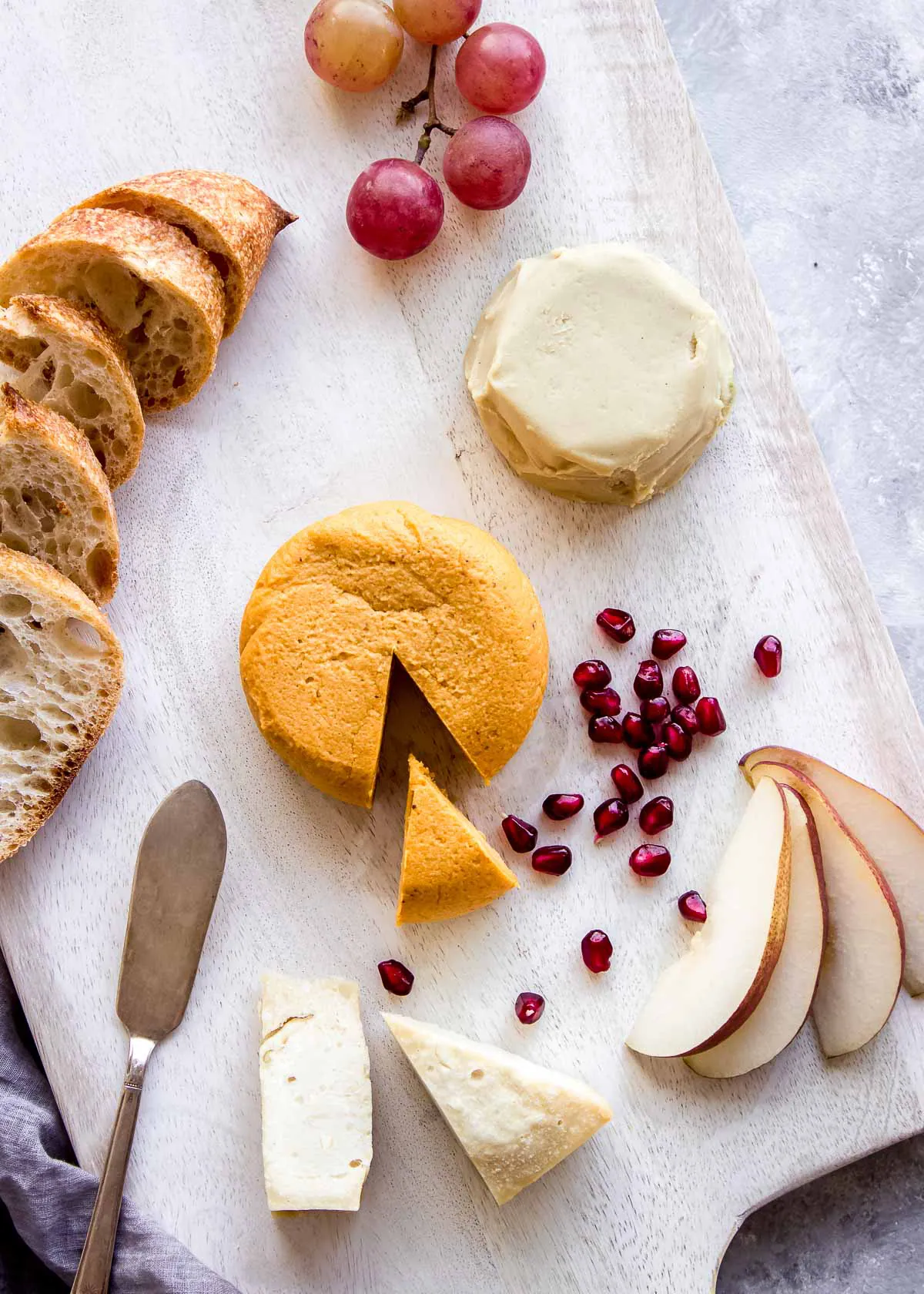Selection of vegan cheeses, bread and fruit.