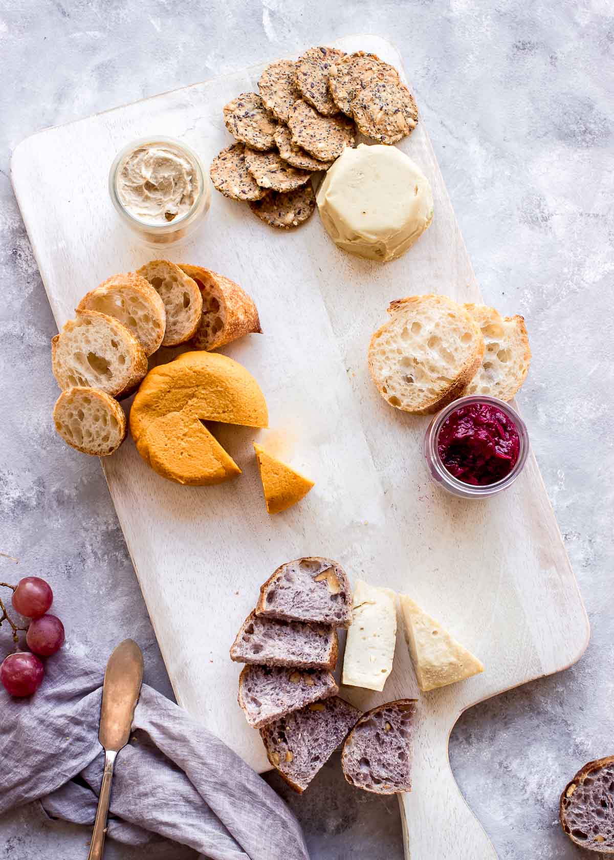 Section of vegan cheese board showing artisan cheeses with crackers and bread fanned out around them.