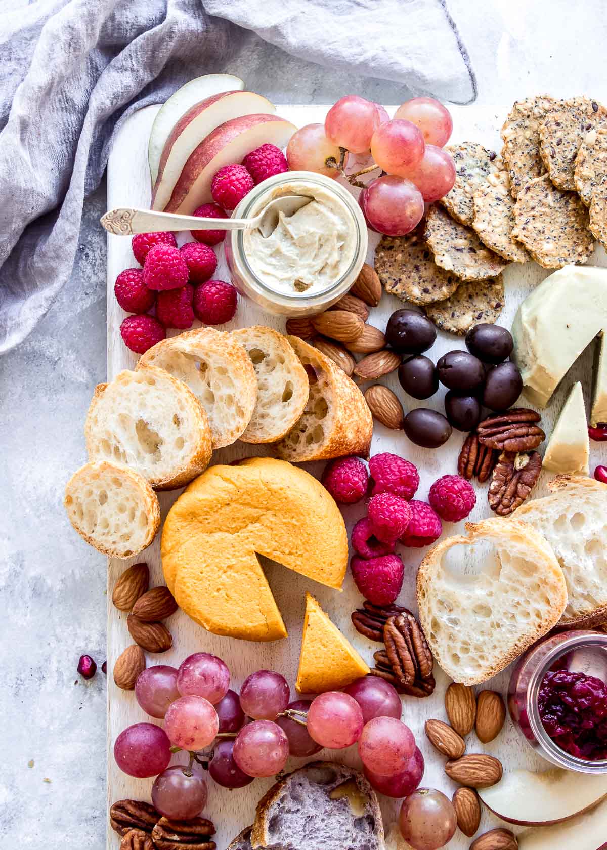 Vegan grazing board showing multiple cheeses, berries, bread, nuts and crackers.