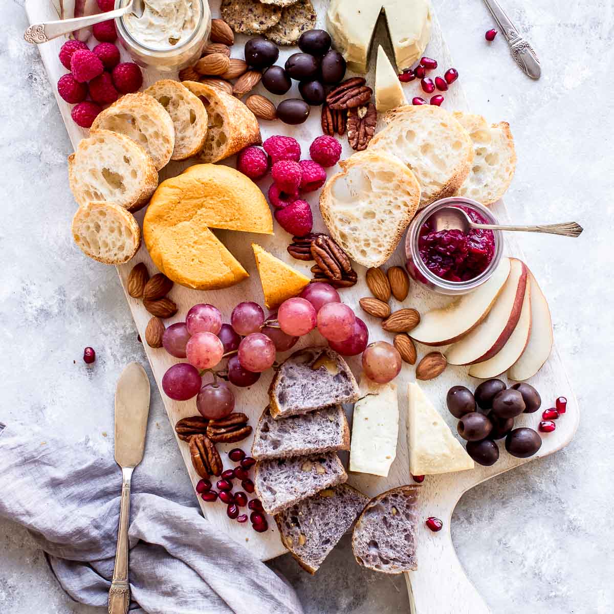 overhead image of vegan cheese board or vegan charcuterie board, with cheeses, bread and fruit.