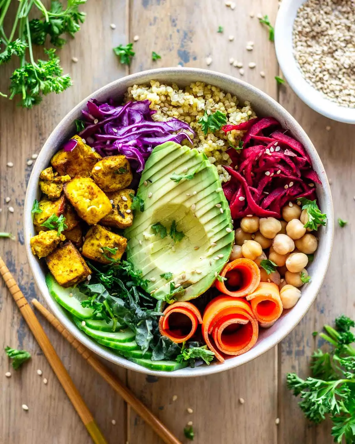 Bowl featuring avocado, turmeric tofu, carrot, millet, chickpeas, cabbage and greens.