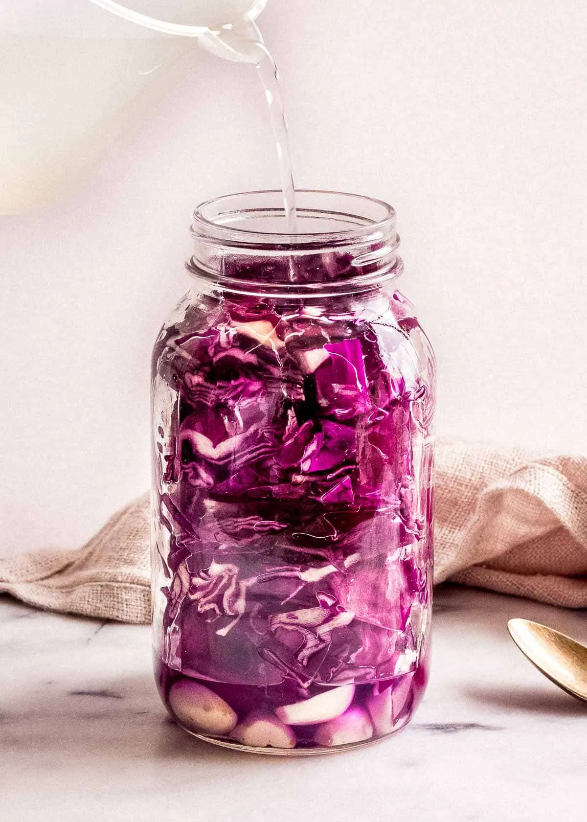 Salt water being poured into jar of red cabbage