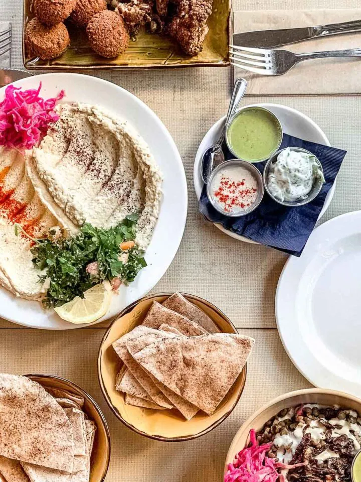 Flat lay showing restaurant meal of vegan Lebanese food including hummus and pita.