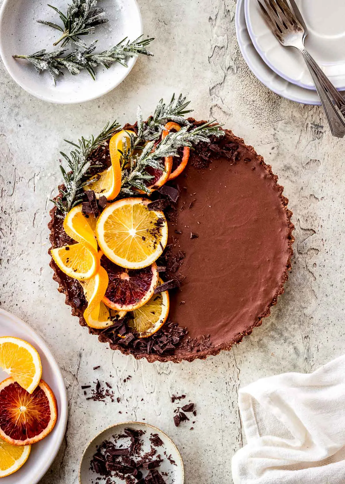 Chocolate orange tart decorated with sprigs of rosemary and orange slices.