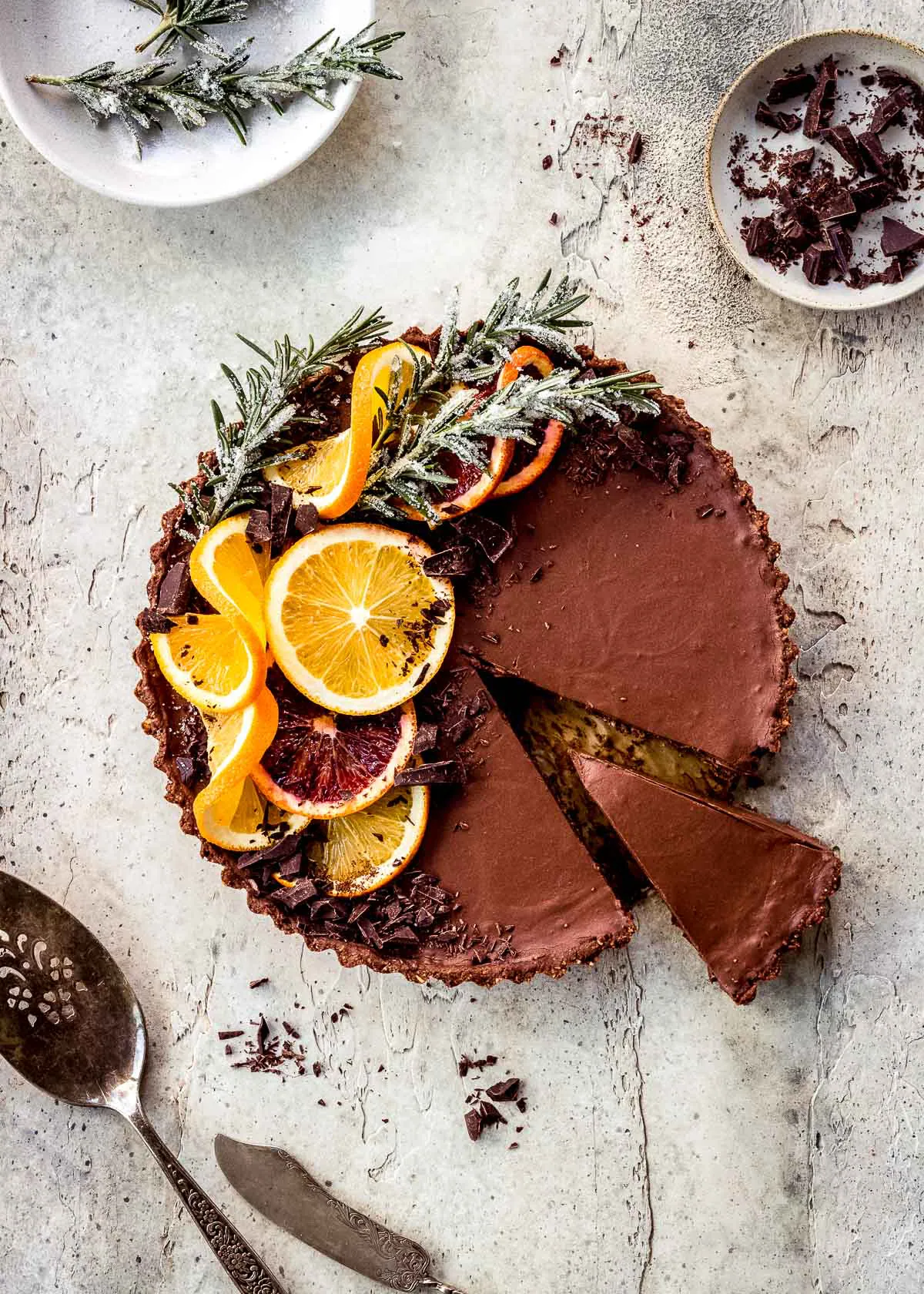 Chocolate orange tart decorated with sprigs of rosemary and orange slices.