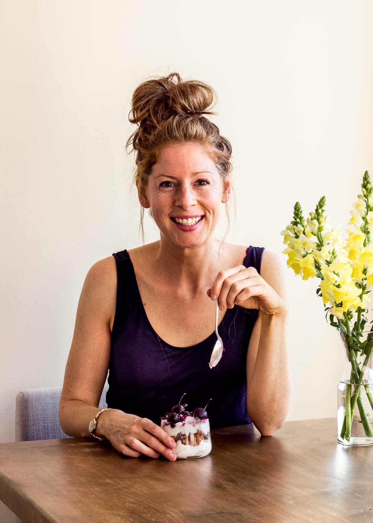 Elizabeth Emery of Vancouver with Love sitting at a kitchen table eating a vegan dessert.