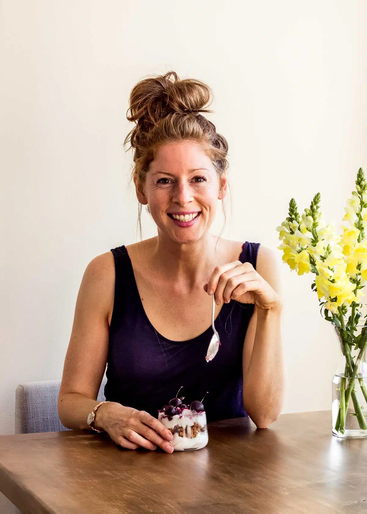 Elizabeth Emery of Vancouver with Love sitting at a kitchen table eating a vegan dessert.