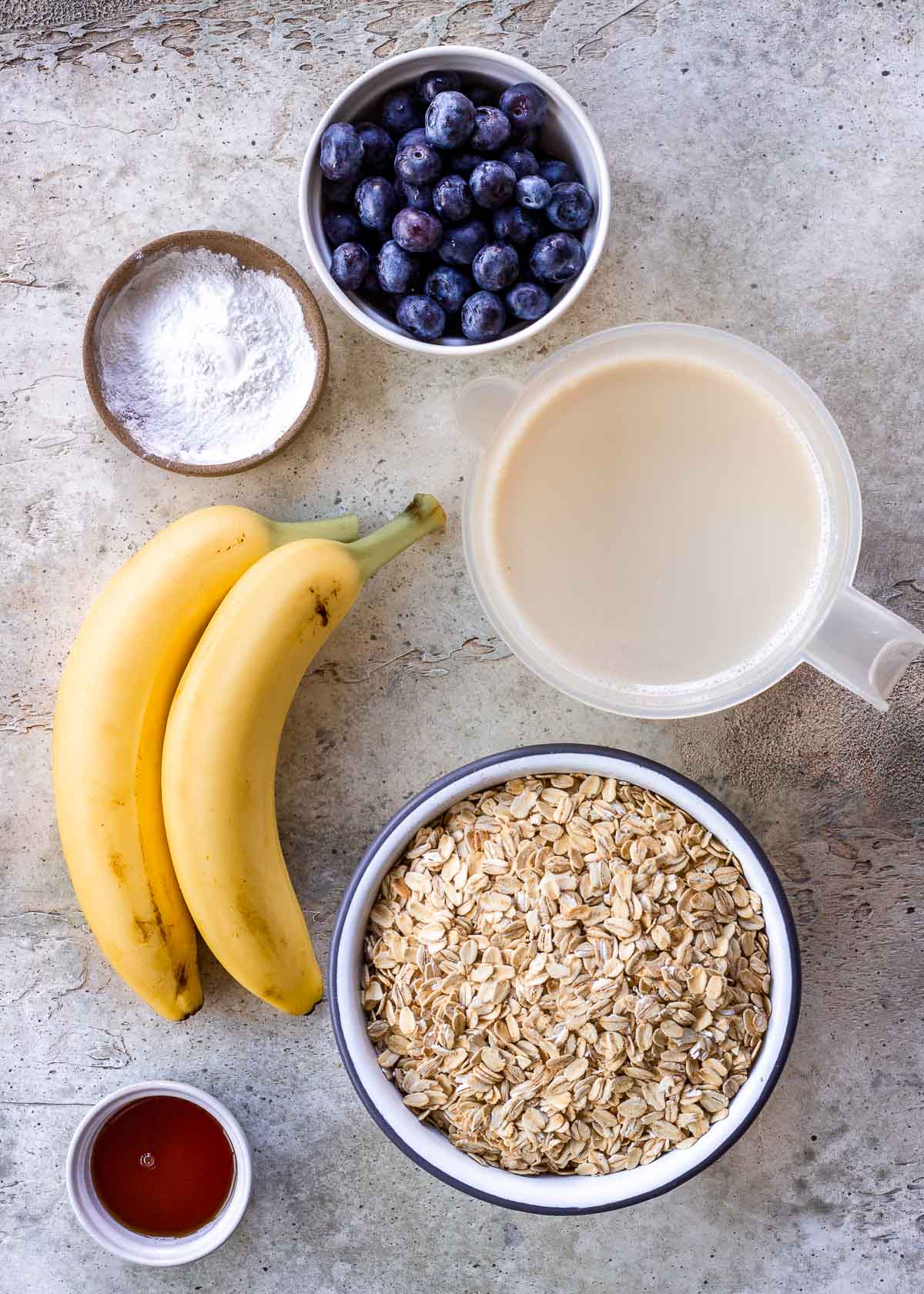 Ingredients for vegan baked oatmeal: banana, oats, dairy-free milk, blueberries, maple syrup and baking powder.