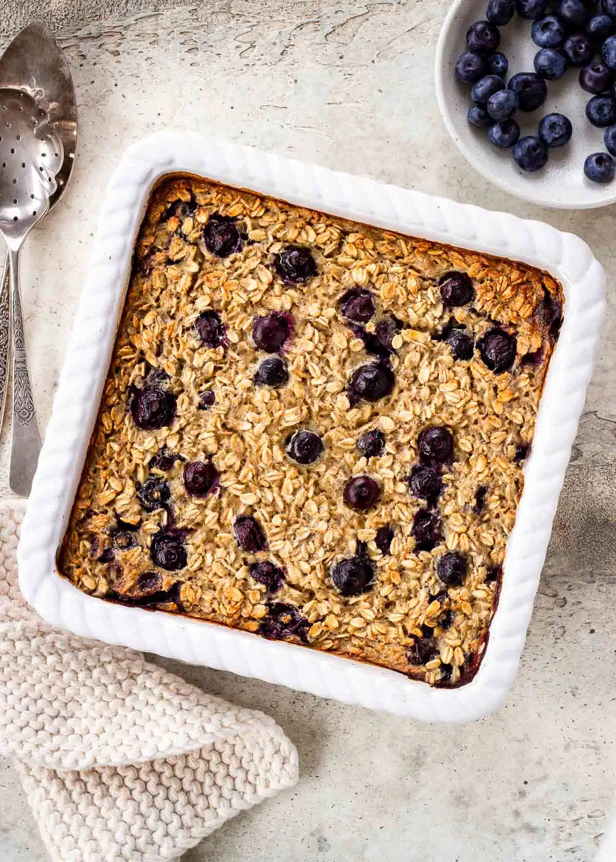 A large white tray of vegan baked oatmeal studded with blueberries.