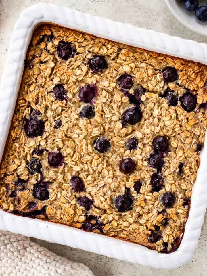 A large white tray of vegan baked oatmeal studded with blueberries.