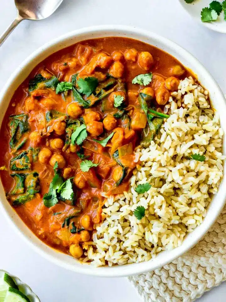 A bowl of Chickpea Spinach Curry and rice decorated with cilantro.