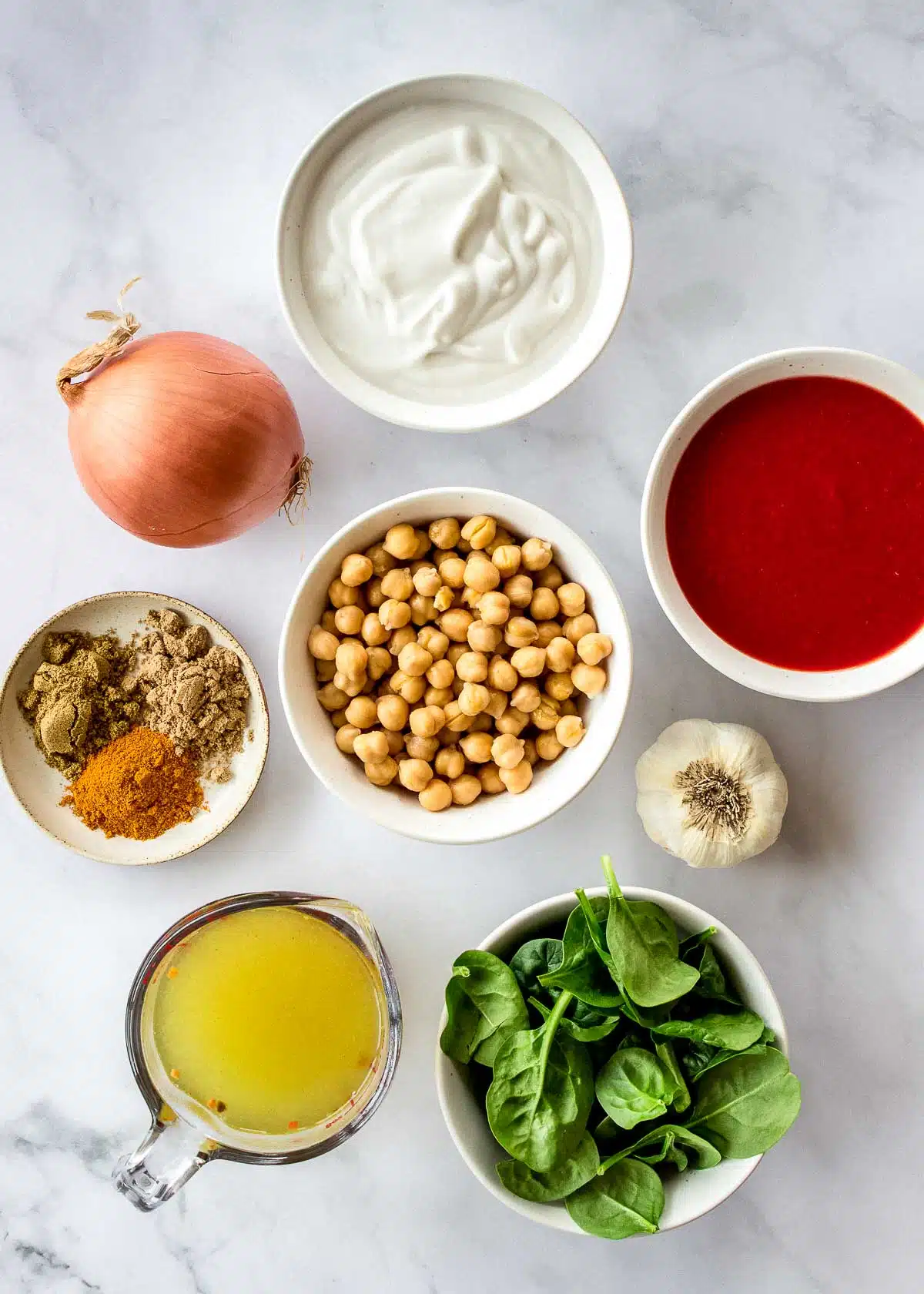 Ingredients in bowls: chickpeas, crushed tomatoes, spices, spinach and coconut milk.