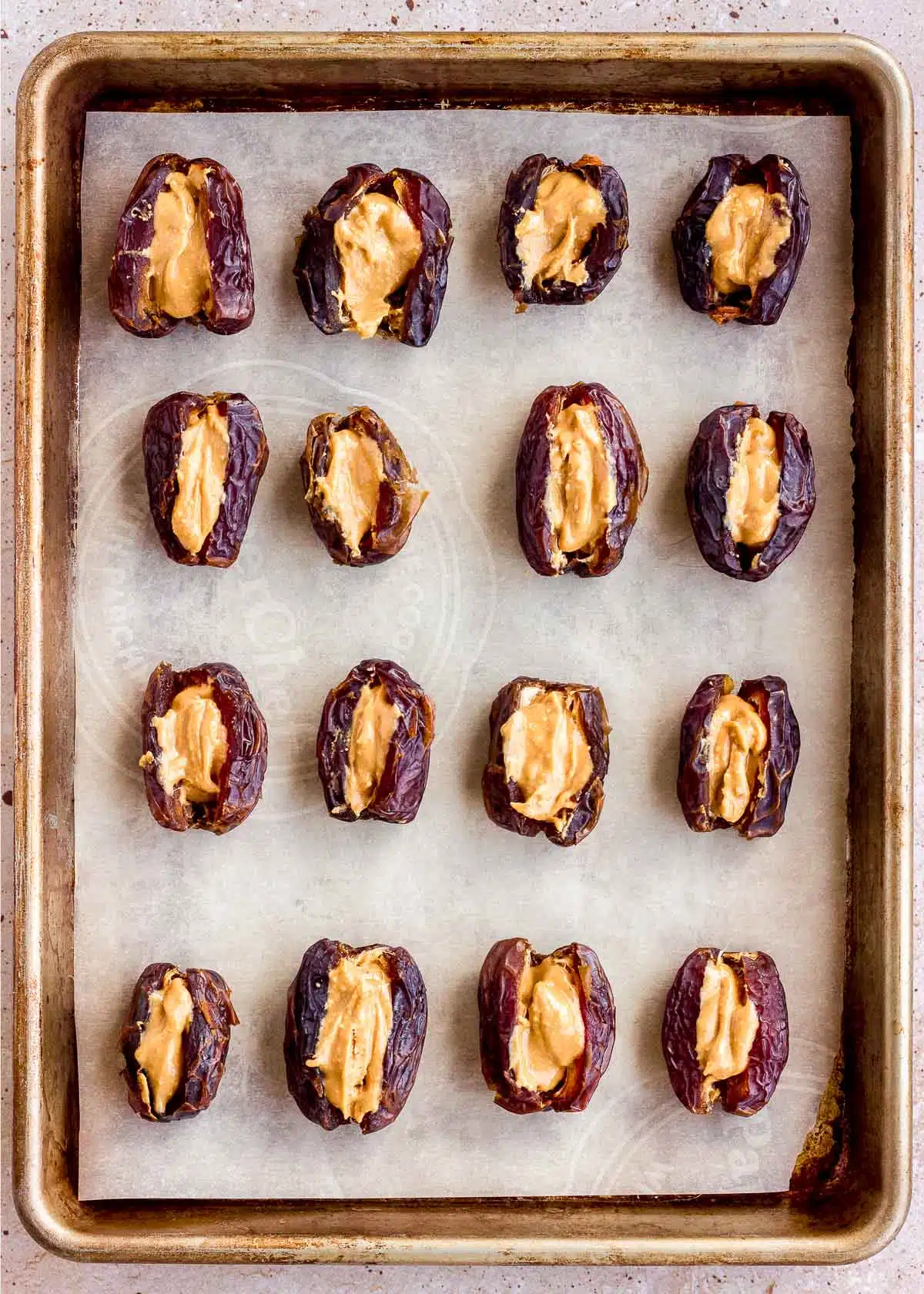 Dates stuffed with peanut butter on a baking tray.