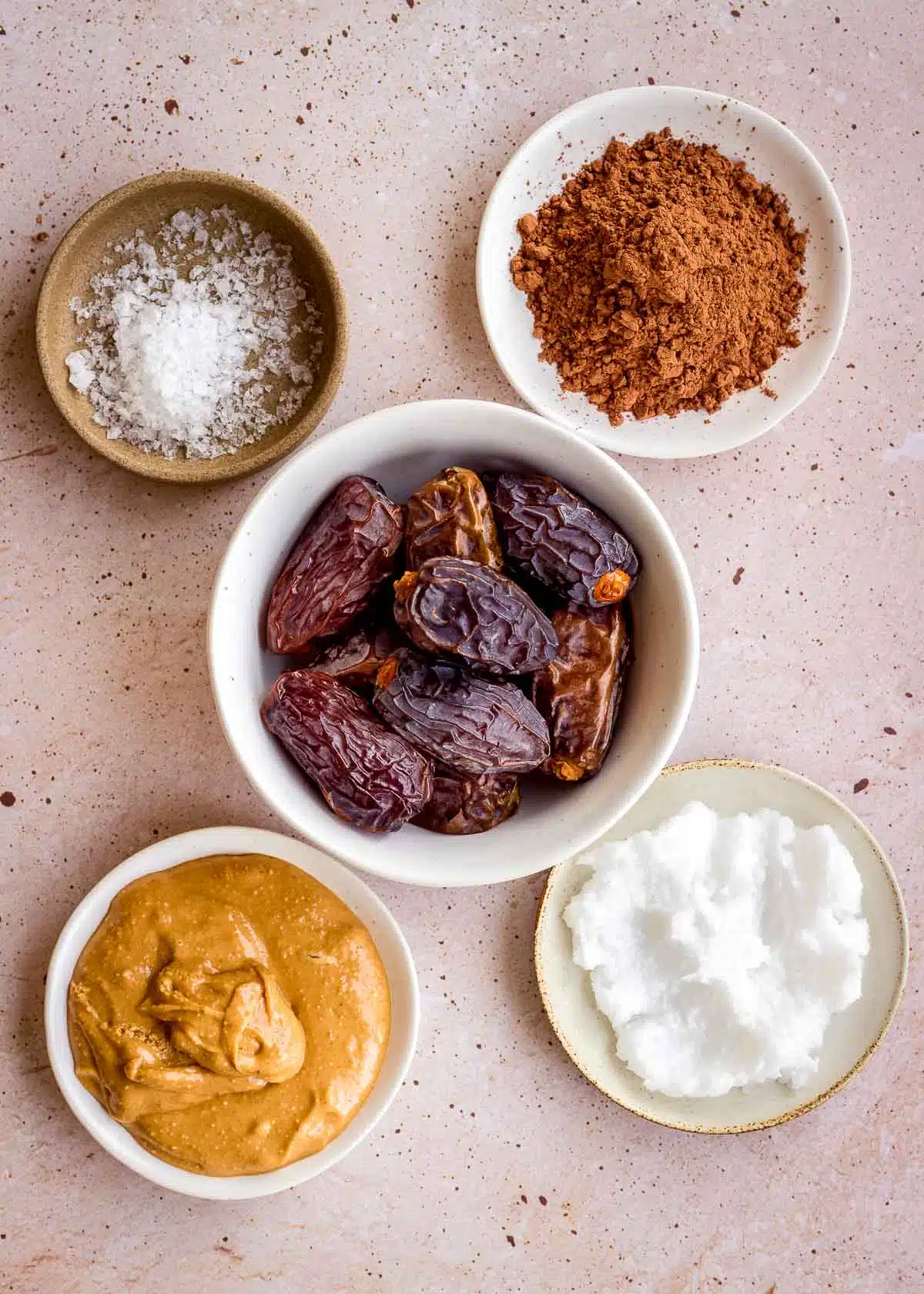 Bowls of ingredients: dates, cacao powder, coconut oil, sea salt and peanut butter.