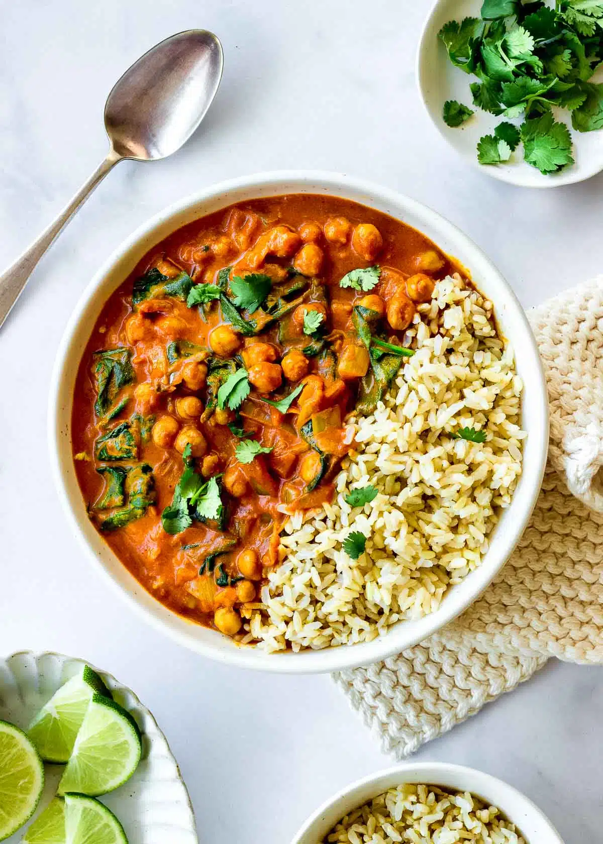 A bowl of one pot Chickpea Spinach Curry and rice decorated with cilantro.