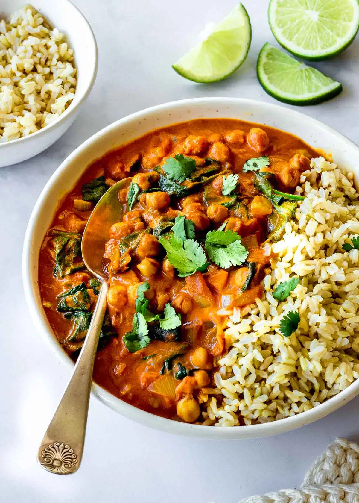 A bowl of vegan chickpea spinach curry with rice decorated with cilantro leaves.