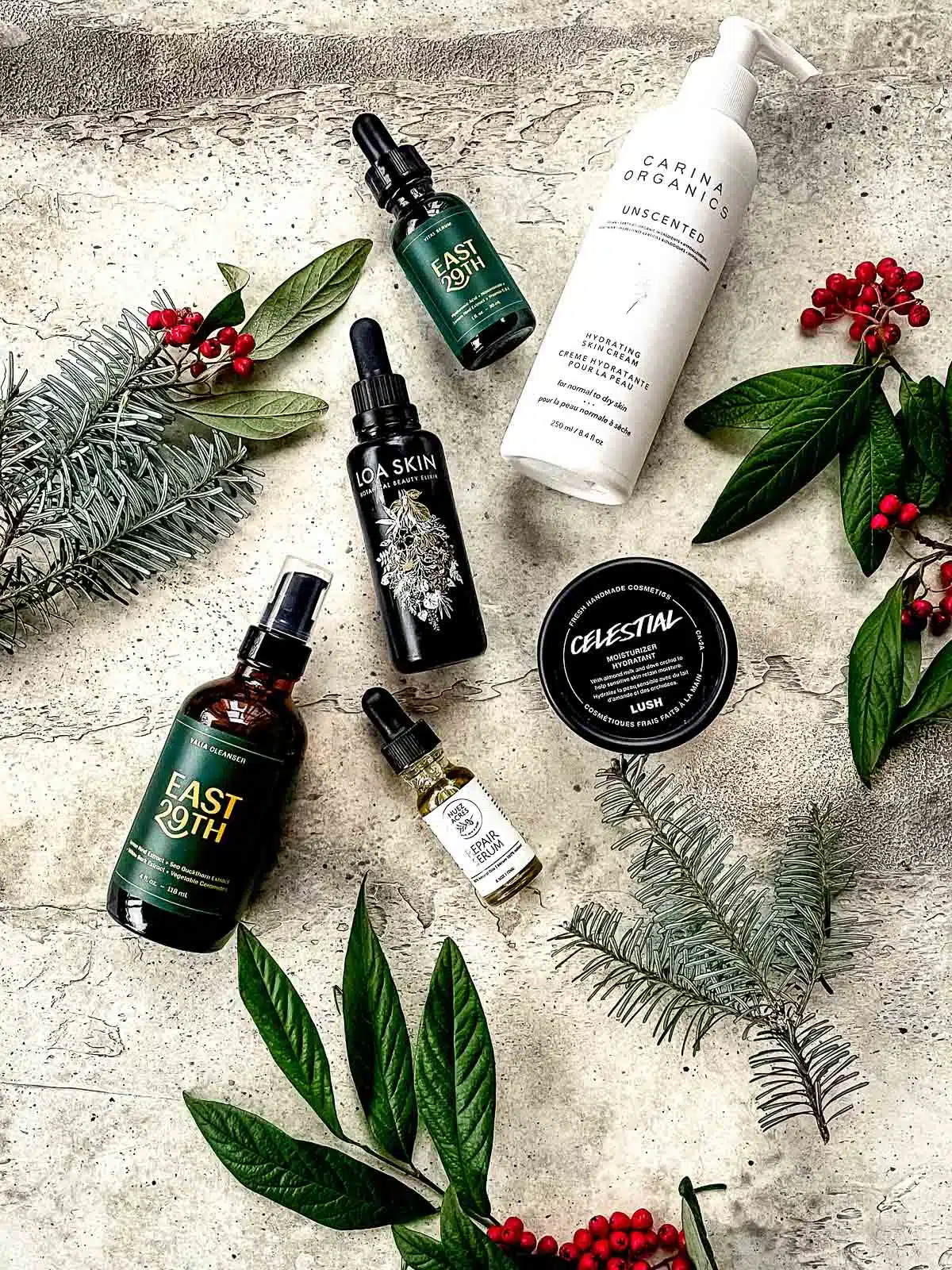 Vegan cosmetics displayed with festive leaves and berries.