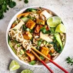 A bowl of vegan noodles with almond butter sauce, tofu and vegetables.