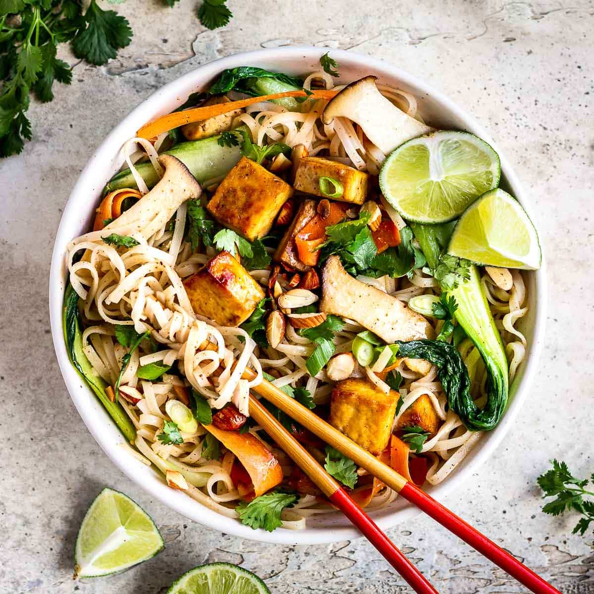 Overhead view of bowl of noodles with tofu, vegetables and almond butter sauce by Elizabeth Emery.