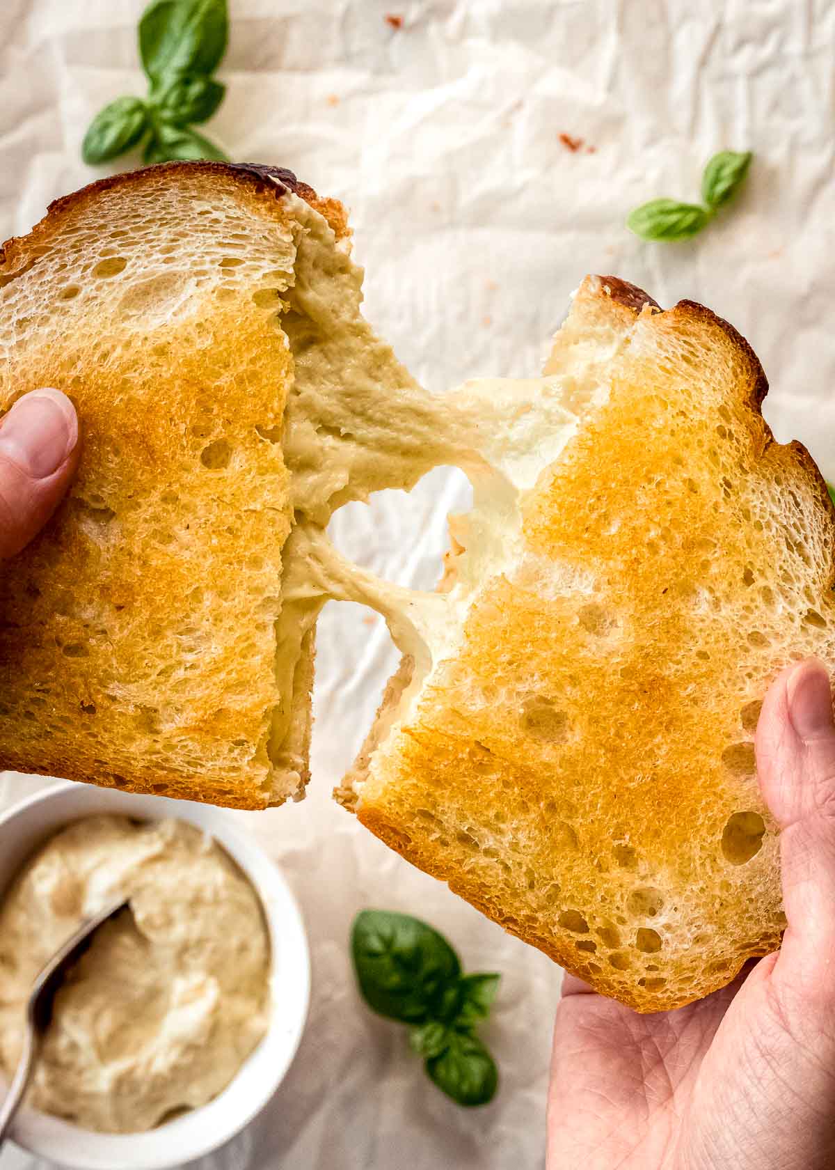 Hands pulling apart a grilled cheese sandwich with cashew mozzarella.