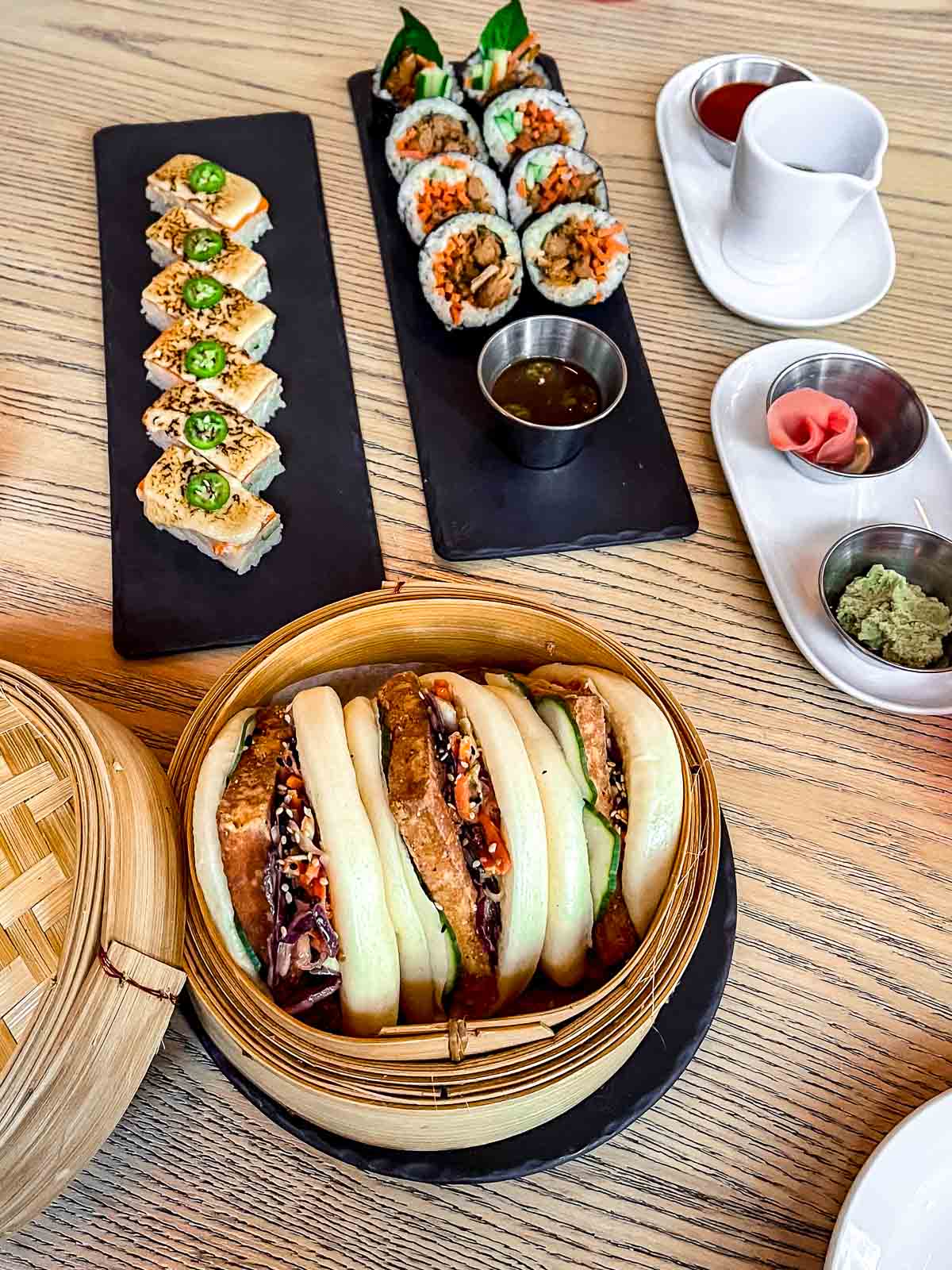 25 Best Vegan Restaurants in Vancouver BC for 2023 - selection of bao buns and plant-based sushi from MILA.