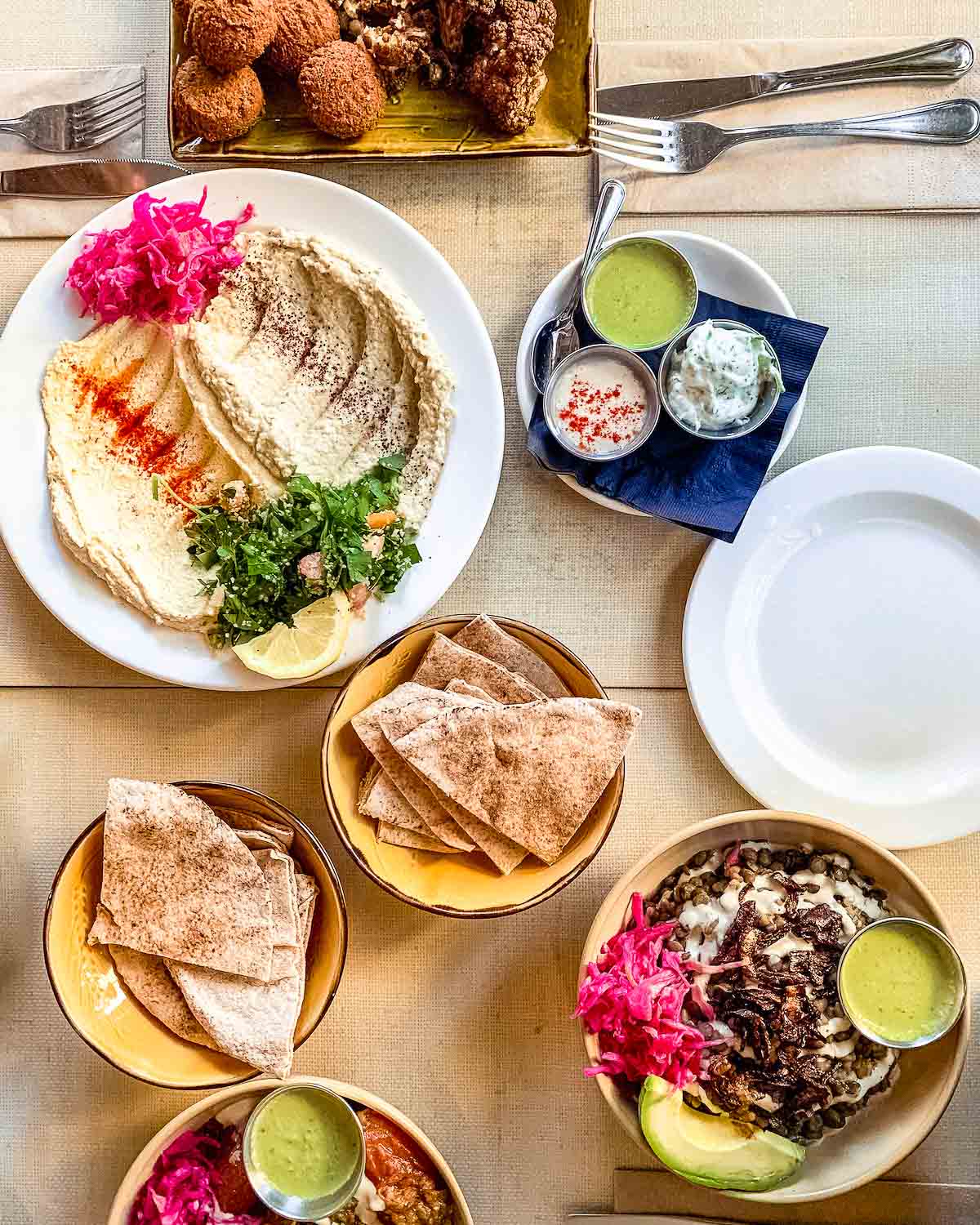 25 Best Vegan Restaurants in Vancouver BC for 2023 - overhead view of hummus plates, mjadra bowl and pitta at Nuba.