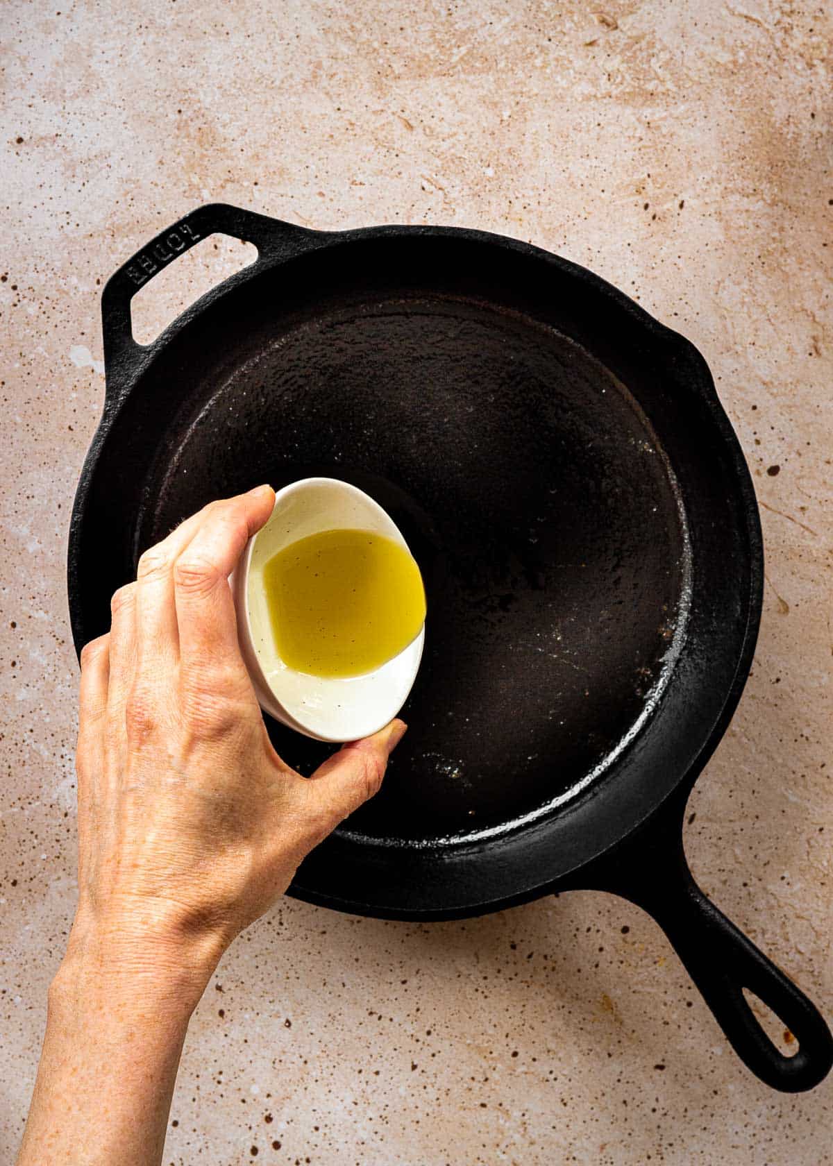 Oil being poured into cast iron pan.