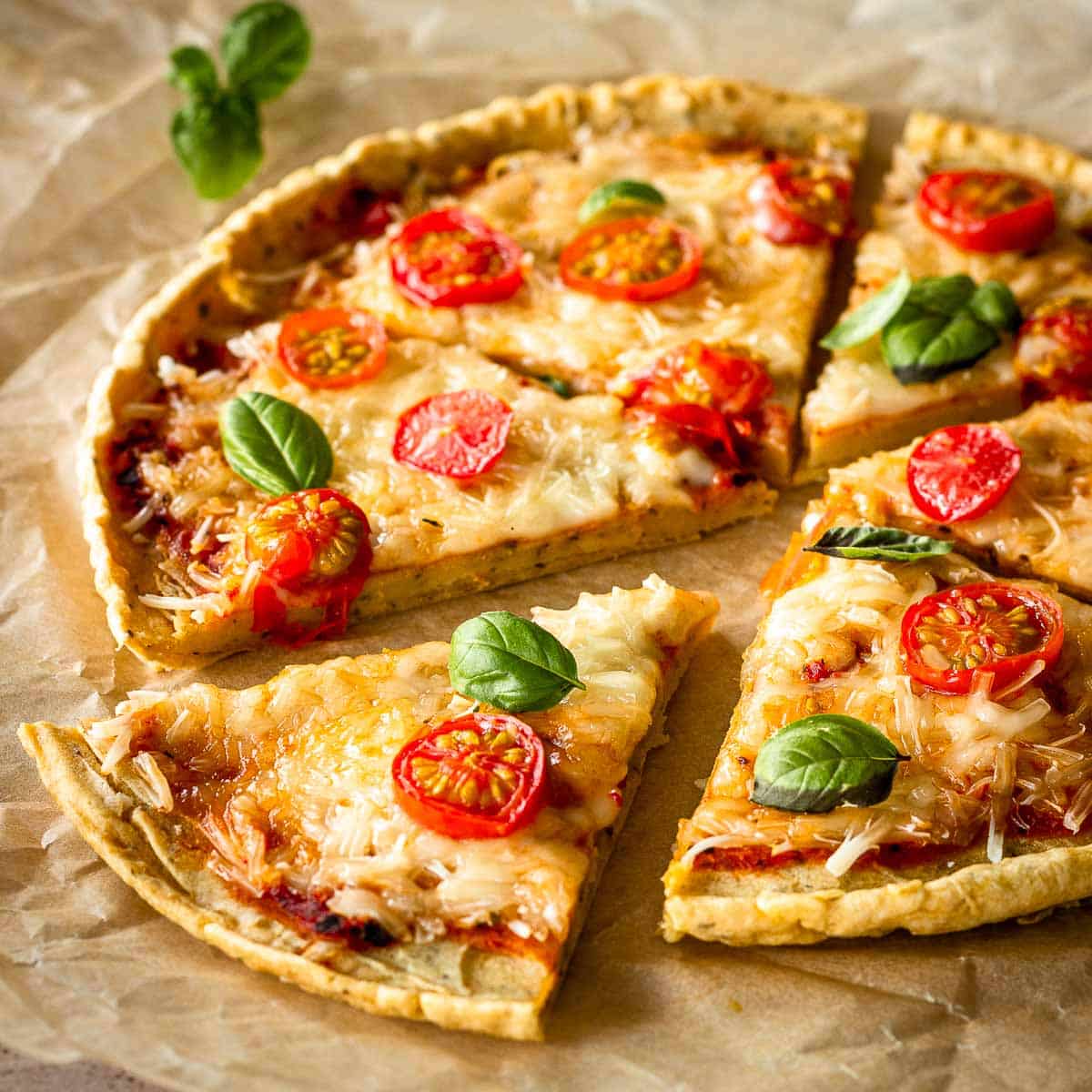 Chickpea flour pizza crust topped with vegan cheese, cherry tomatoes and basil leaves.