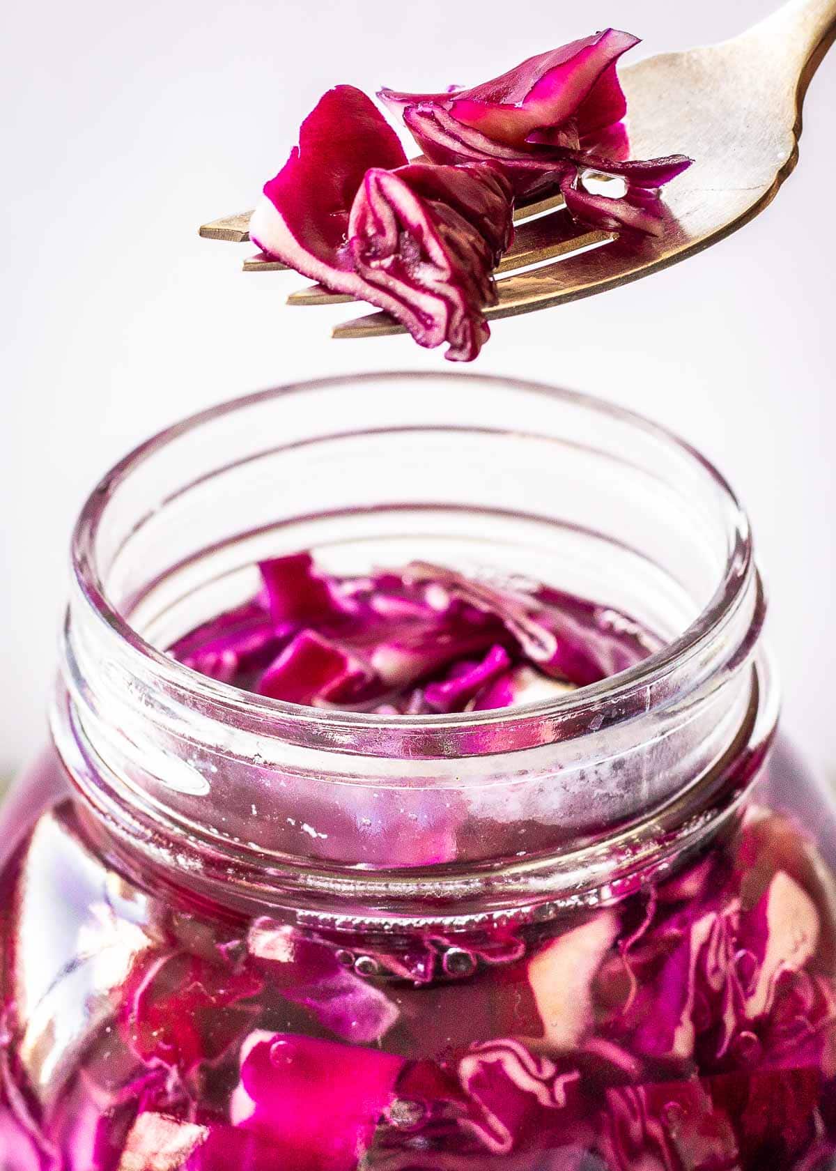 Jar of red cabbage sauerkraut with a fork over it.